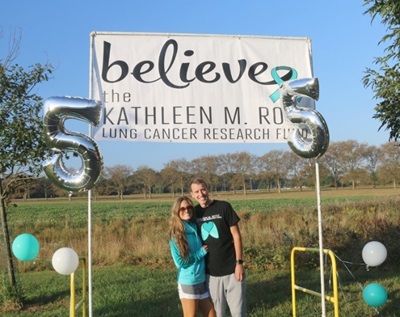 two people smiling under a sign that says believe